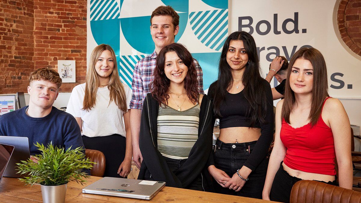 A group of young work experience students in the Marketing Pod office.