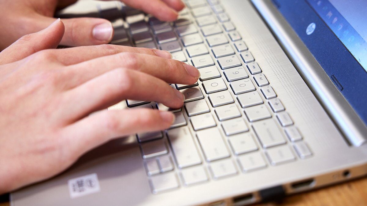 A person typing on a laptop keyboard.